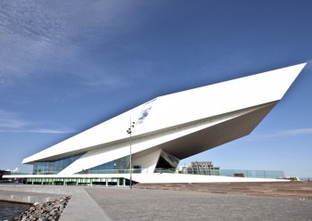 EYE Film Instituut Amsterdam Wie achter het Centraal Station over het IJ kijkt, zal een veelhoekige fel-witte cocon met een breed donker venster waarnemen. Hierin is het nieuwe EYE filministituut gevestigd. Het is een ontwerp van Delugan Meissl Associated Architects (DMAA) uit Wenen. Ook van binnen is het gebouw, op de donker houten vloeren na, overweldigend wit